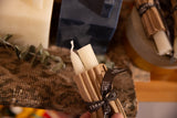 6 inch cream beeswax taper candles wrapped in cardboard with black ribbon.