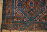 Detailed corner of vintage Mehreban rug, rust and sky blue field with stylized motifs, fringe.