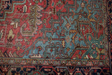 Heriz rug corner with triple-tier spandrel, brick red field, powder blue geometric vinery.