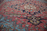Textural close-up of vintage Heriz carpet pile with geometric vinery in brick red and navy blue.