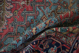 Folded vintage Heriz carpet showing rich brick red, navy, and powder blue geometric vinery.