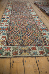 Nuanced diamond lattice and stepped floral pattern on an antique Caucasian runner's field in madder red and saffron yellow.