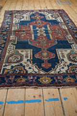 Hamadan rug corner: geometric floral motifs in navy, rust, ivory, with visible even wear.