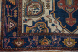 Bottom-left corner of the Hamadan rug showing navy, rust, and ivory geometric floral border.