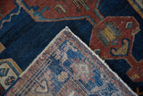Corner detail of a vintage Hamadan rug showing hand-knotted weave, navy blue, and rust geometric pattern.