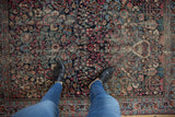 Vintage Persian Meshed rug's worn floral pattern in navy, cochineal red, underfoot view.