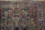 Detail of vintage Meshed rug corner, showing worn floral buds and blossoms.