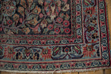 Vintage Meshed rug corner with tattered fringe, showing blue, red, green floral borders.