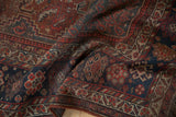 Folded vintage Kamseh rug displaying border floral guls and Herati field in madder red and navy.