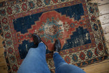 Antique Shirvan rug corner, worn cobalt blue field revealing foundation, geometric border motifs.