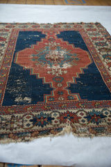 Close-up of antique Caucasian Shirvan rug with extensive pile wear, geometric medallion, and tattered floral border.