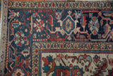 Vintage Heriz carpet corner detail, rich navy field, ivory border, and traditional floral patterns.