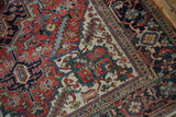 Vintage Heriz carpet corner, showing ivory main border with classic red and blue motifs, deep red field.