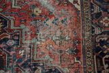 Detail of vintage Heriz carpet: faded brick red floral field with foundation showing through.