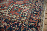 Heriz carpet detail: rich navy main border with reciprocating samovar and red, ivory floral field.