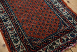 Worn madder root rust field, staggered botehs, and navy vine border of this vintage Engelas rug.