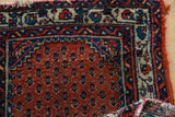 Vintage Engelas rug corner detail: madder rust boteh field, ivory vine border, visible tattered edge.