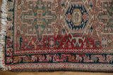 Vintage Karaja rug corner: worn dusty rose field, classic geometric brick red and navy borders.