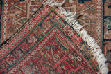 Folded vintage Karaja rug corner shows hand-knotted structure, geometric pattern, and ivory fringe.