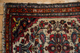 Vintage Dargezine rug corner, intact fringe, traditional floral border, and ivory field.