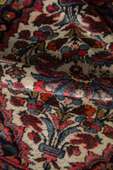 Vibrant madder red, ivory, and navy floral motifs on the Dargezine rug pile.