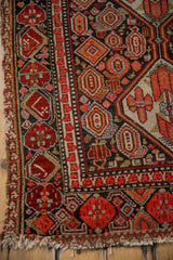 Cherry red, charcoal navy, and gold floral patterns on vintage Malayer runner corner with fringe.