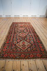 Vintage Malayer runner close-up showing worn fringe and floral pomegranate border motif.