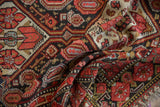 Textured close-up of vintage Malayer rug with deep red, charcoal, and gold floral and boteh motifs.