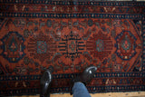 Rust-red field of vintage Lilihan runner, showing geometric finned motifs and navy border.