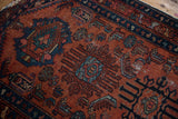 Finned sapphire blue and emerald motifs on a textured raspberry red vintage Lilihan rug.