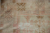 Distressed Oushak rug texture showing faded geometric patterns and exposed foundation.