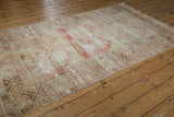Faded pale raspberry red and beige geometric patterns on a distressed vintage Oushak rug showing foundation.