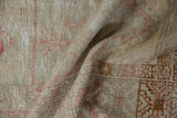 Distressed pile detail of vintage Oushak rug with faded red motifs and beige tones.