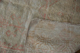 Distressed Oushak rug showing worn ivory pile, visible foundation, and secured side cord.