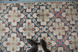 Distressed Turkish Soumac rug detail with feet, showing ivory, sapphire, and raspberry medallions.
