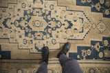 Distressed vintage Oushak rug featuring dusty beige and navy geometric floral patterns underfoot.