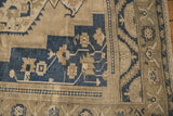Distressed Oushak rug's stepped corner spandrel with geometric floral blossoms in dusty navy and beige.