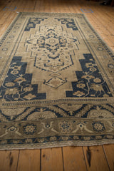Geometric floral border, fringe detail of distressed Oushak rug, dusty beige and navy.