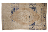 Distressed vintage Oushak rug featuring a faded floral medallion and cobalt blue abrashes.