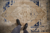 Distressed vintage Oushak rug with diamond medallion, faded cobalt blue, beige pile, and heavy abrashes.