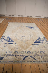 Distressed Oushak rug with heavy abrashes, featuring faded cobalt blue and beige floral motifs.