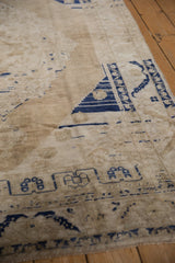 Close-up of distressed Oushak rug's sand field and cobalt blue serrated leaf border.