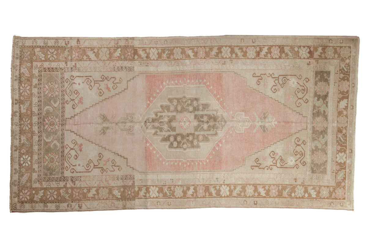 Vintage distressed Oushak rug with a hexagonal center medallion in soft pink, beige, and pale coffee brown.