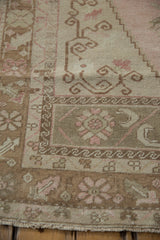 Corner detail showing the low-pile texture and hook and latch motifs of a distressed Oushak rug.