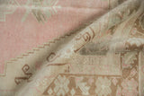 A folded view of a vintage Turkish Oushak showing its distressed, low-pile texture.