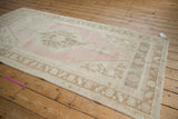 Angled view of the vintage distressed Oushak rug, showing its soft pink, beige, and coffee brown palette.