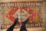 Distressed vintage Oushak rug, faded pomegranate red and saffron hues, central shield medallion.