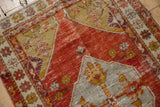 Distressed vintage Oushak rug showcasing worn pomegranate red field and ivory spandrel with saffron palmettes.