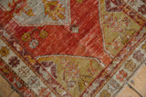 Distressed Oushak rug corner, vibrant pomegranate red and saffron yellow floral patterns.