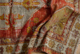 Vintage Distressed Oushak rug's textured pile, highlighting faded red, saffron, and ivory tones.